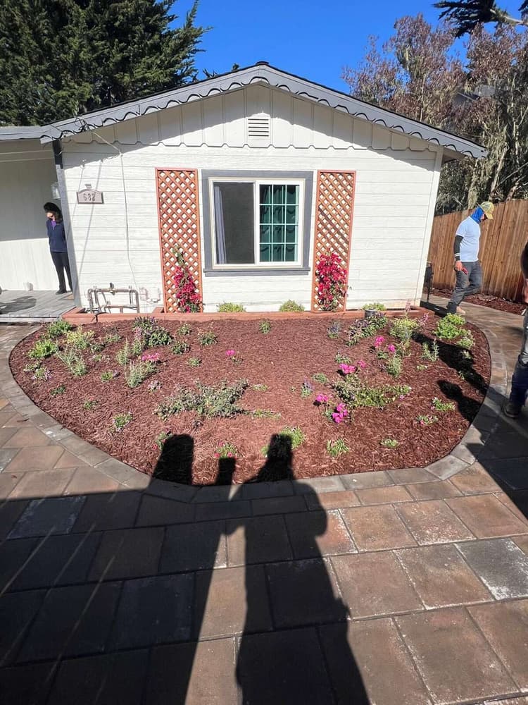 Curved paver patio and planting bed around a cottage front