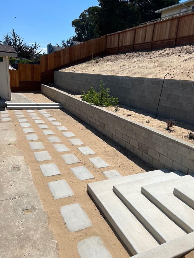 Long view of a block retaining wall, path and concrete steps on a sloped yard